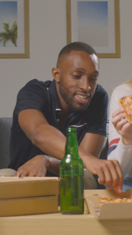 Vertikales-Video-Von-Freunden-Zu-Hause,-Die-Sich-Beim-Essen-Von-Pizza-Zum-Mitnehmen-Teilen-2